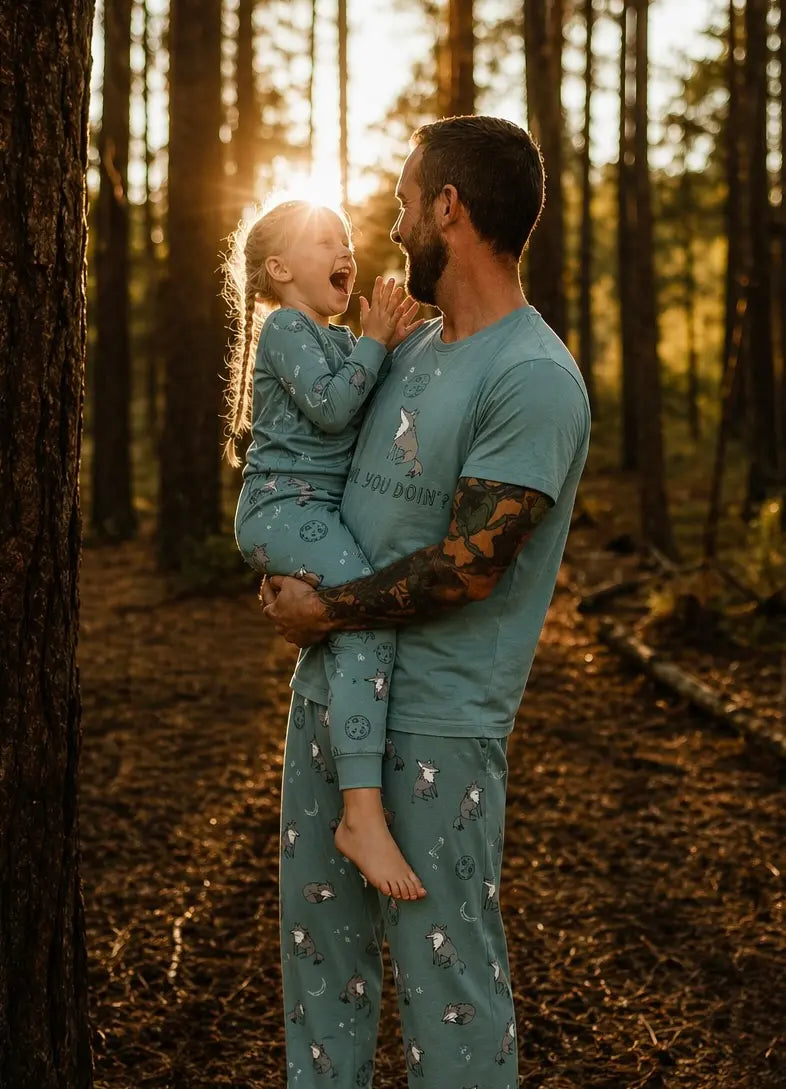 Man holding a child in a forest at sunset