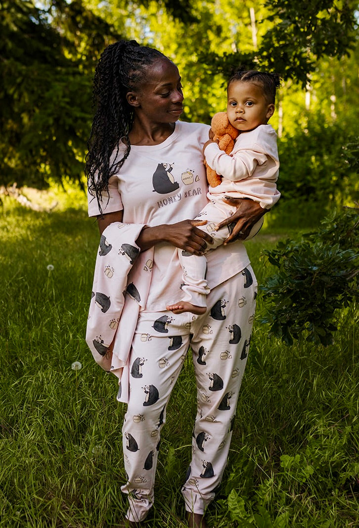 Woman and child wearing matching pajamas with bear patterns in a grassy outdoor setting