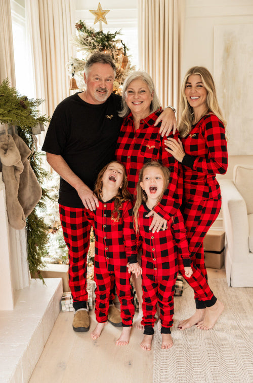 Family of five wearing red plaid pajamas in a festive living room.