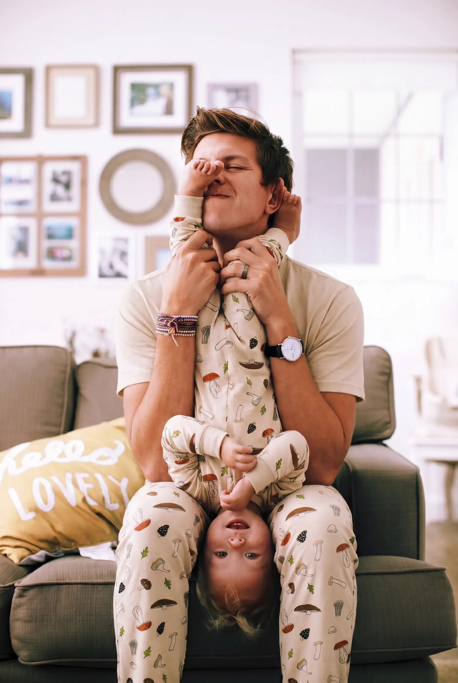 Man and child in matching pajamas sitting on a couch in a living room.