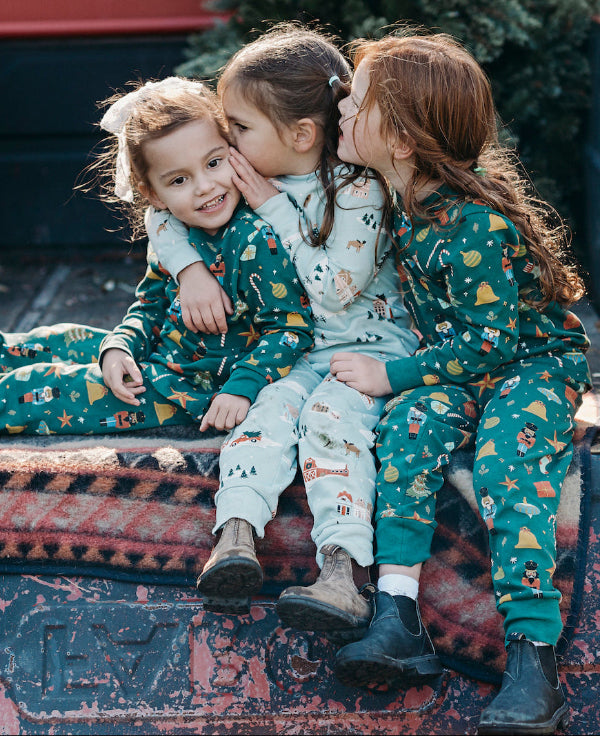 Three children in matching pajamas sitting in the back of an old truck.