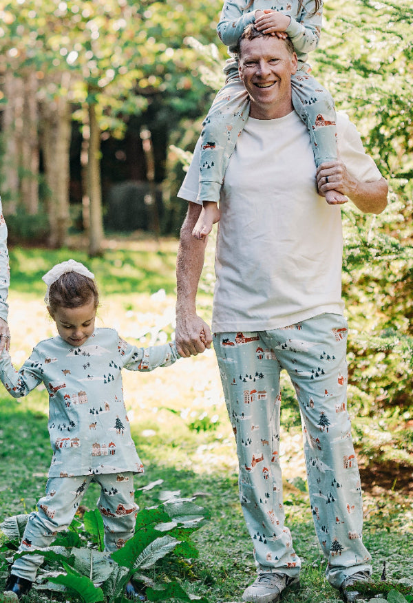 Family of four wearing matching pajamas outdoors in a natural setting
