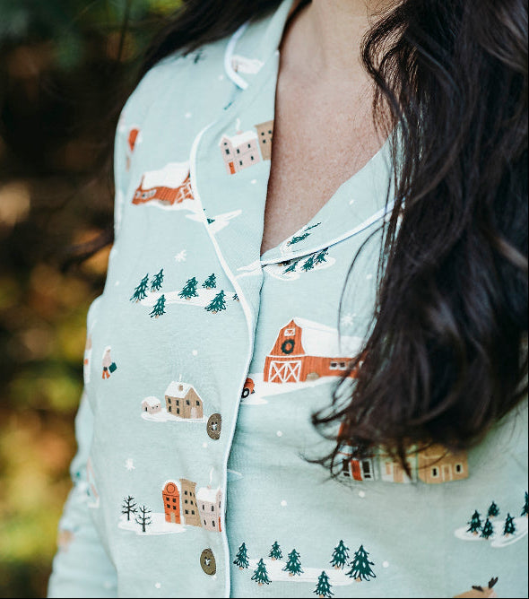 Person wearing a light blue pajama top with house pattern in a forest setting