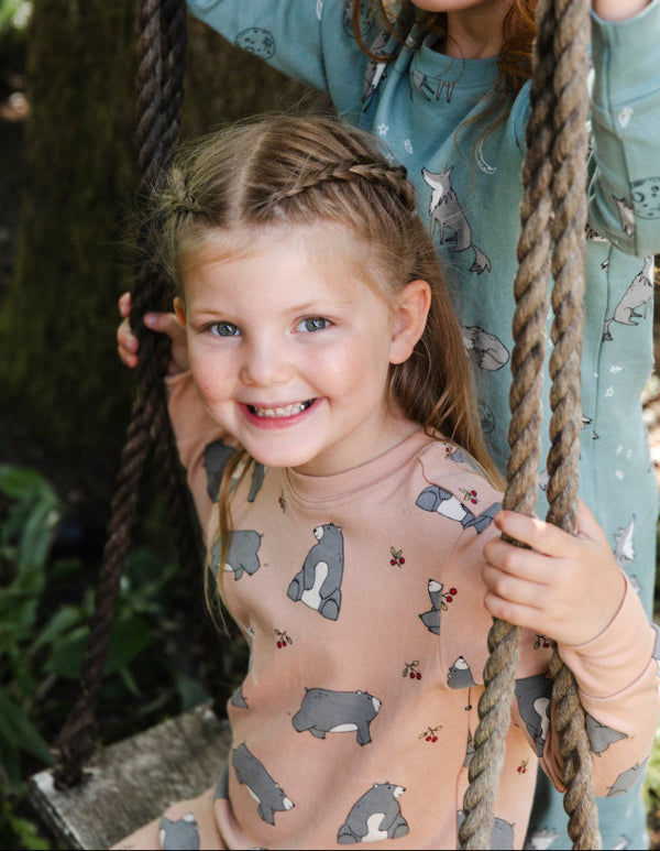 Young girl on a swing wearing a patterned shirt with a blurred background