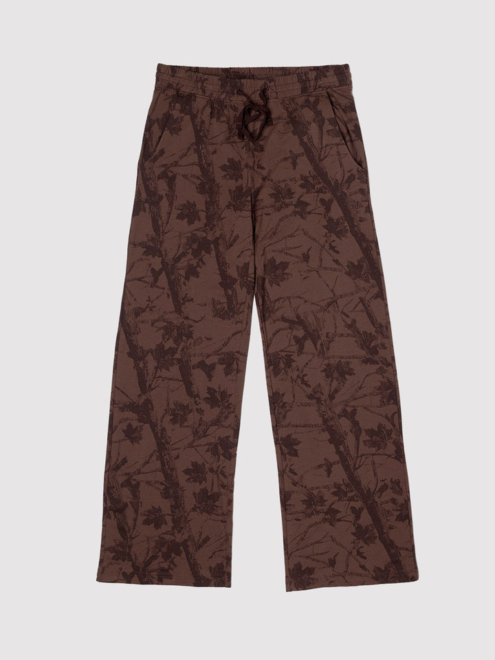 A pair of brown wide-leg pants featuring an all-over dark brown leafy branch pattern, shown flat against a light gray background.