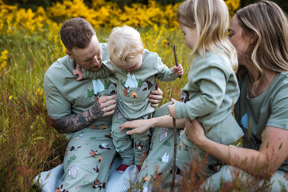 Family of four in matching outfits sitting in a field with wildflowers.