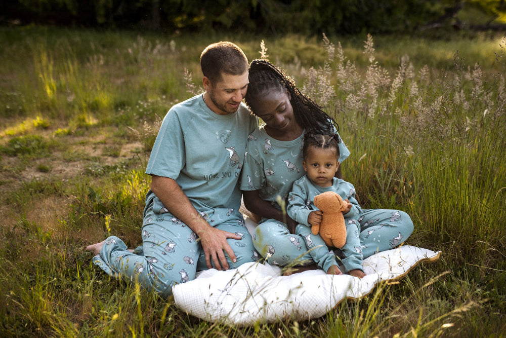 Family of three sitting on a blanket in a grassy field