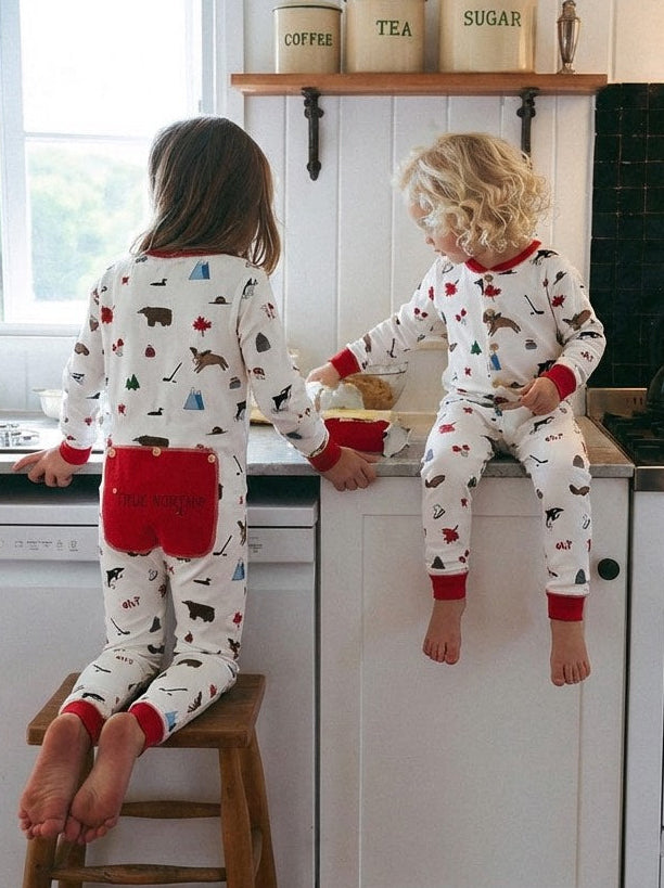 Two children in pajamas sitting on a kitchen counter with a white kitchen background.