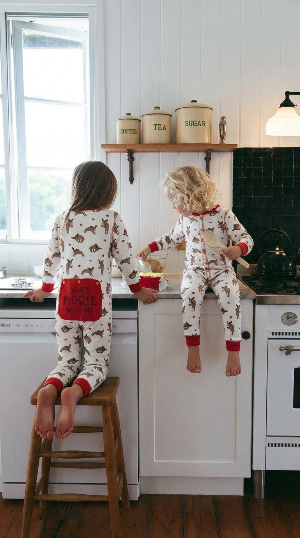 Two children in matching pajamas sitting on a kitchen counter.
