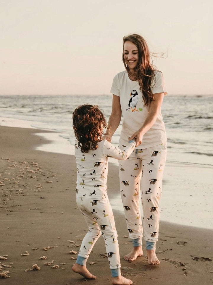 Woman and child in matching pajamas on a beach